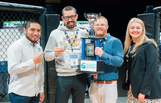 Music City Battle LCD Swap Competition champion holding the Gadget Repair Expo trophy and cash prize inside The Octagon