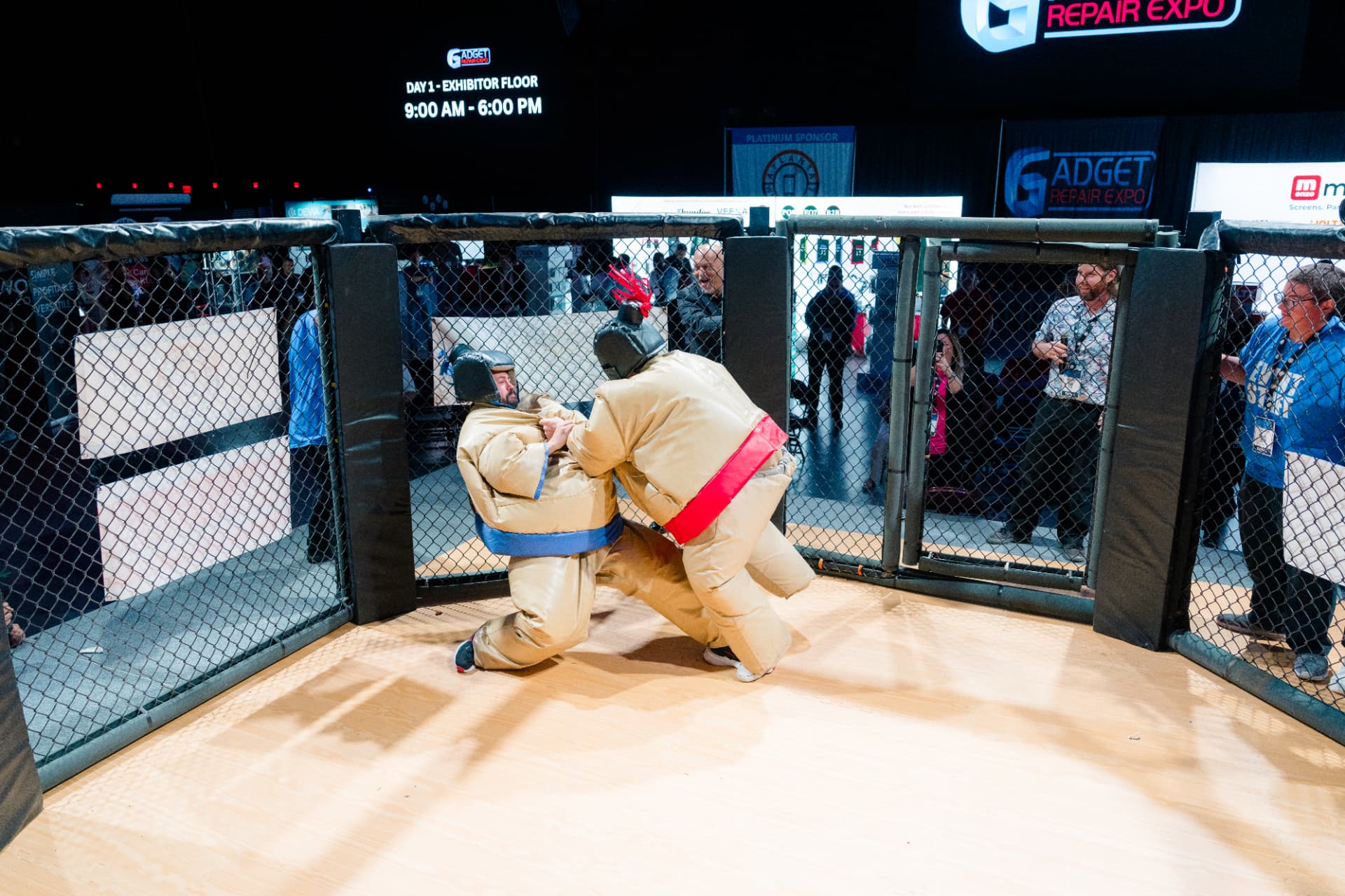 Two competitors in padded sumo suits wrestling inside The Octagon at Gadget Repair Expo