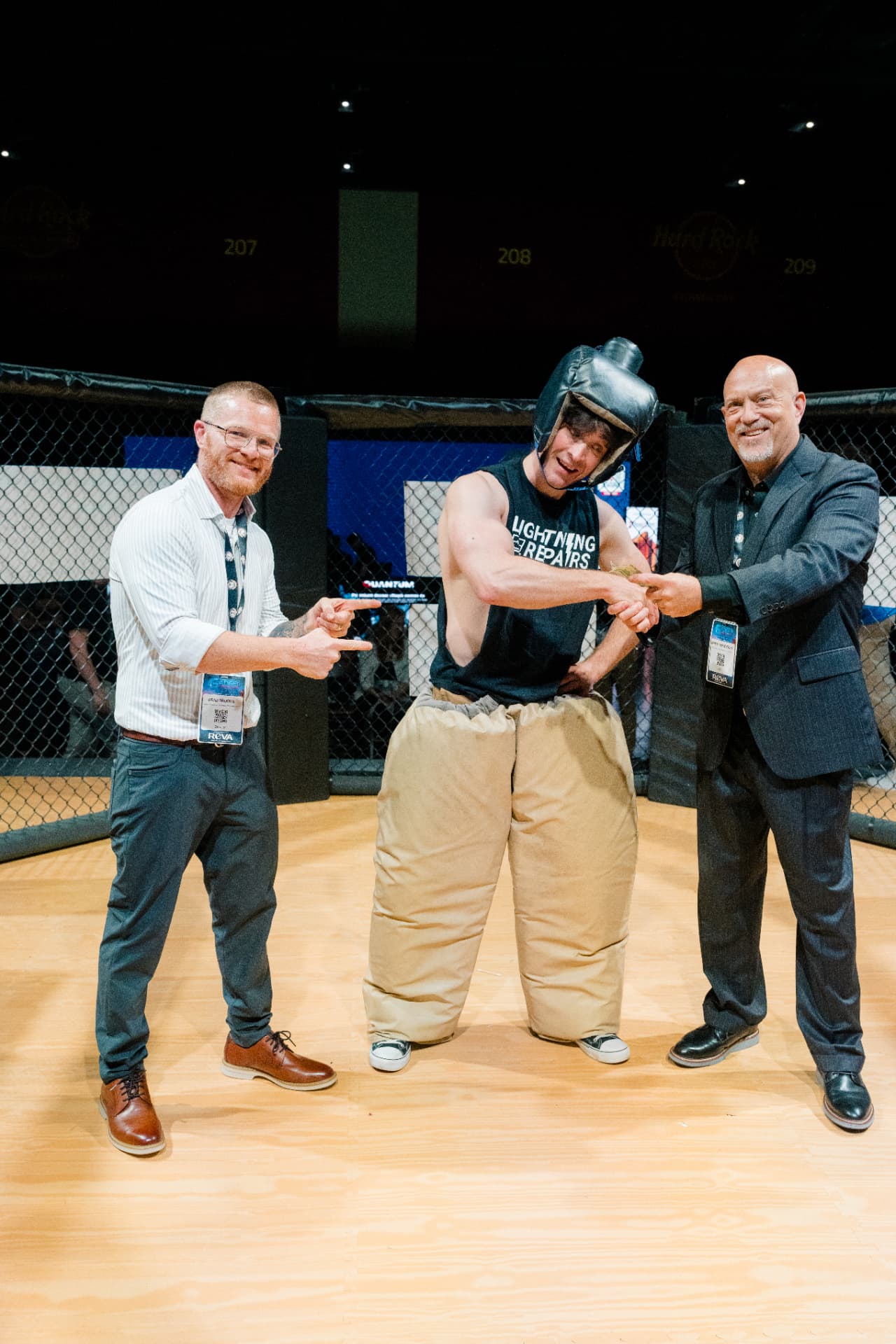Smack Down winner in a padded sumo suit being handed cash inside The Octagon