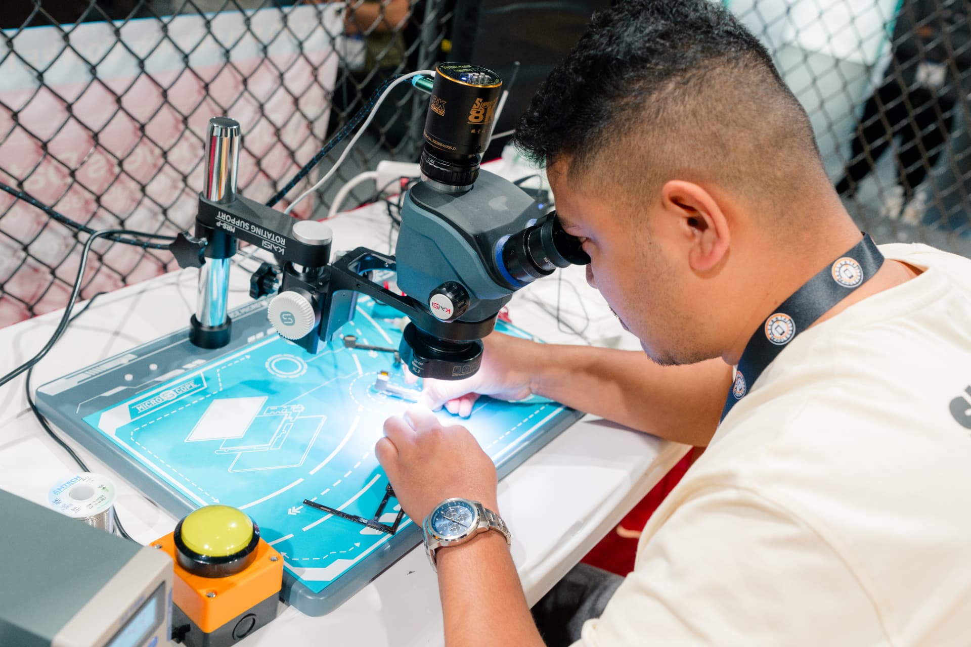 Competitor microsoldering under a microscope inside the octagon