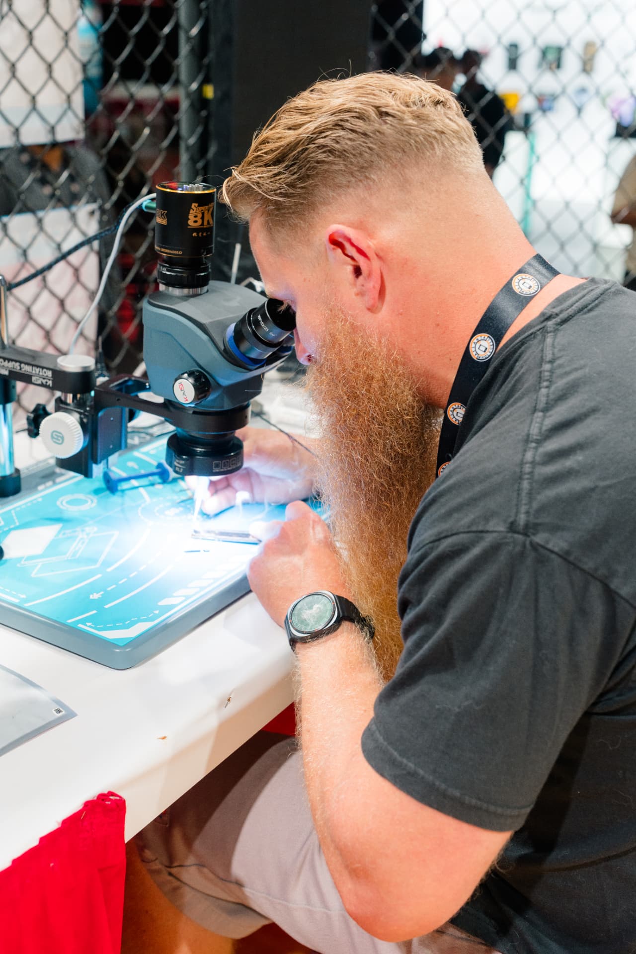 Technician microsoldering at a competition bench inside the octagon