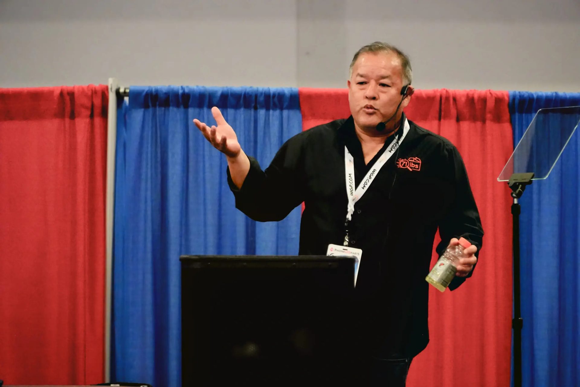 Speaker with a microphone presenting on stage at the Gadget Repair Expo