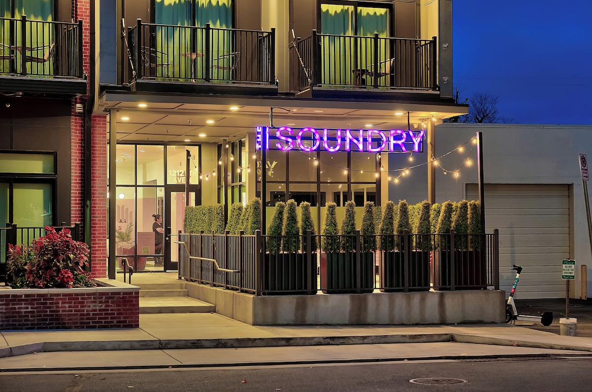 Entrance of The Soundry in Nashville with its neon SOUNDRY sign, gated walkway and potted plants